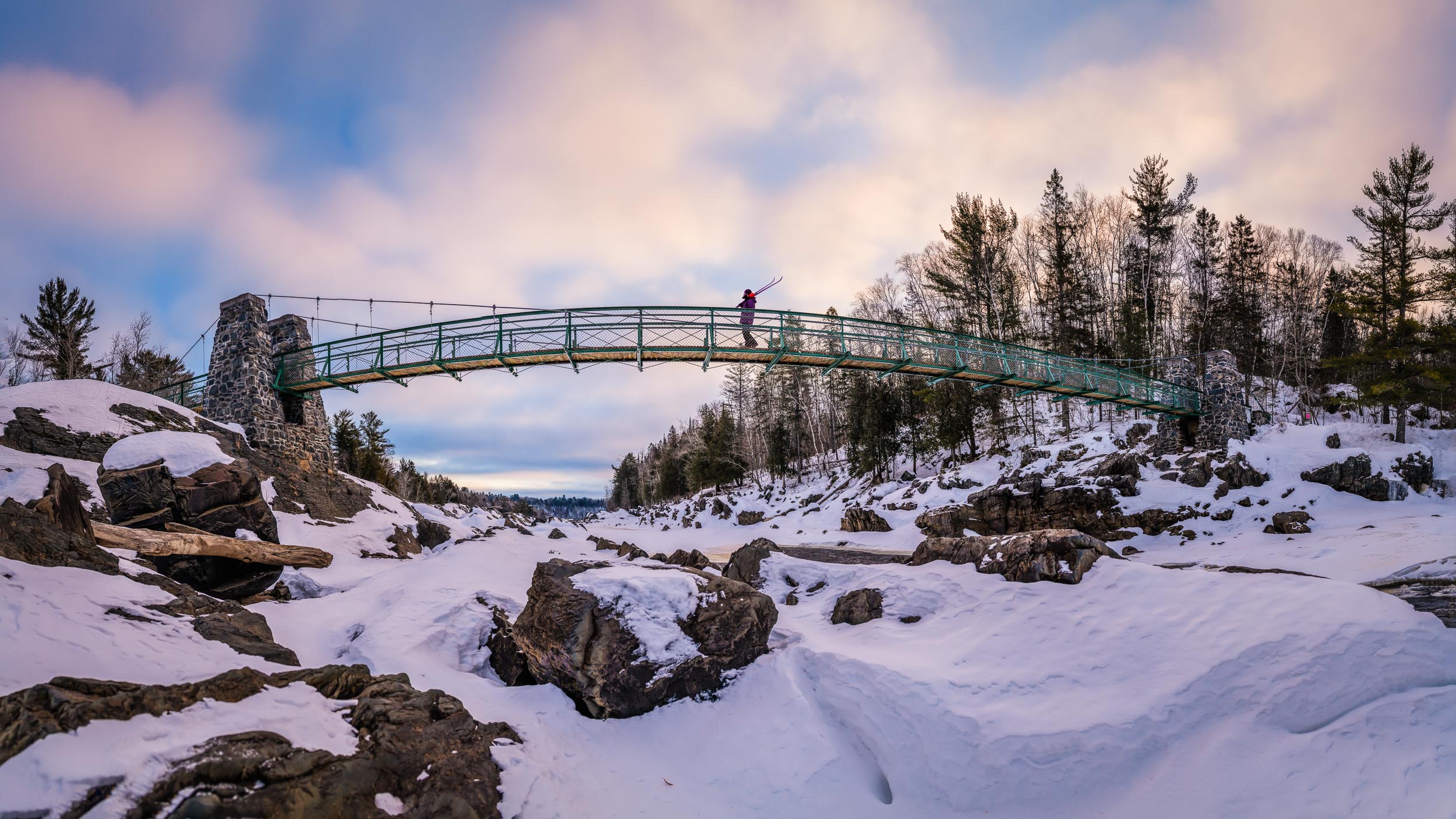 Crossing the Swinging Bridge in Jay Cooke State Park, Minnesota, on a frigid morning looking for sunrise and good skiing.